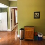 Clean green room with hallway on the left and wall in the center