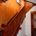 Wooden staircase with wooden door with mirror on the right