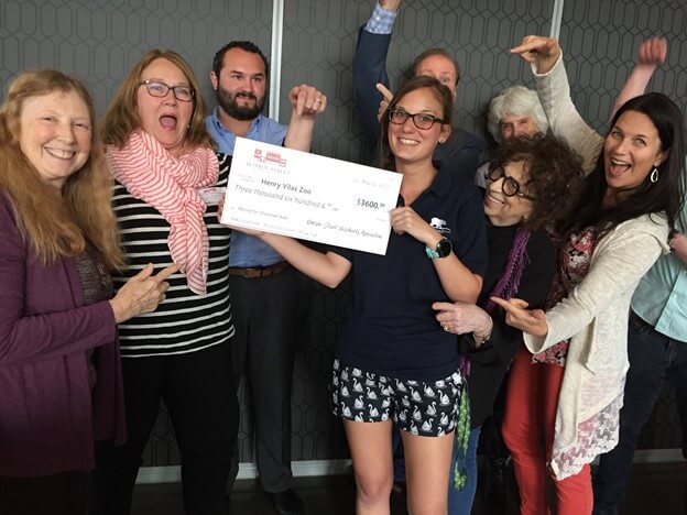 people smiling and pointing at a giant check