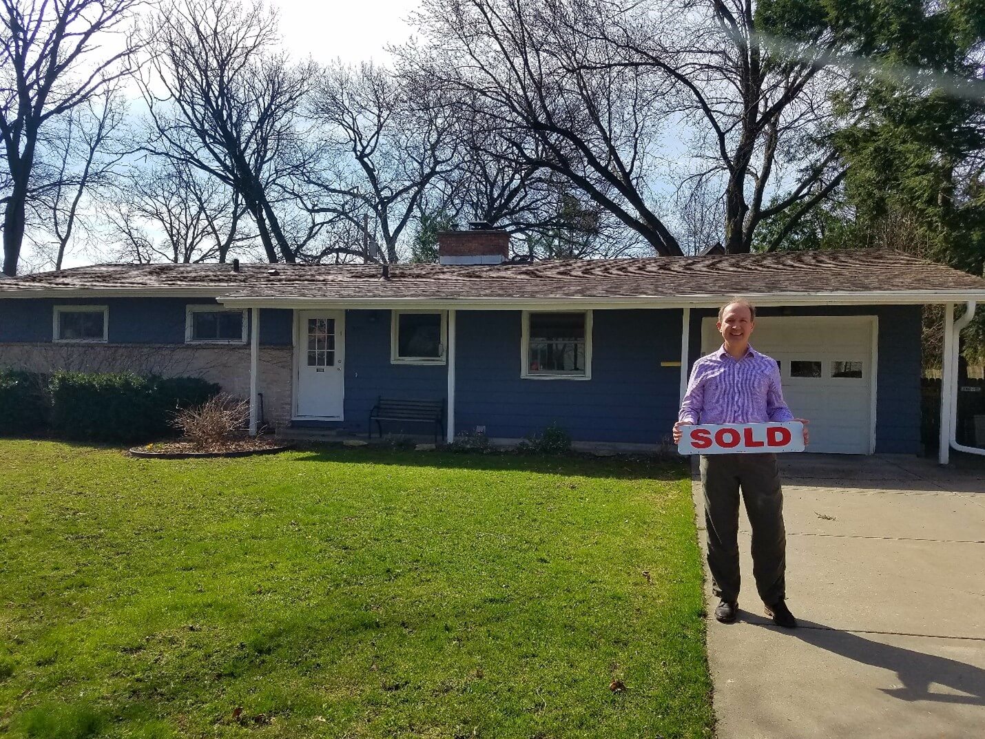 man outside house holding a sold sign